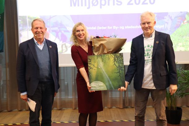 To menn og en dame poserer med blomster og diplom