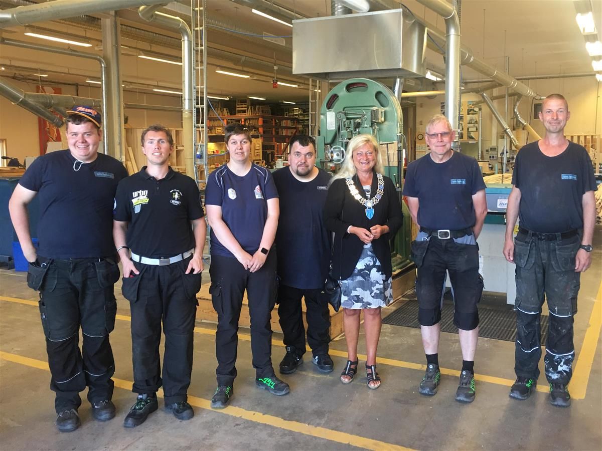 6 ar6 arbeidere står oppstilt med ordfører for kamera i arbeidslokaler