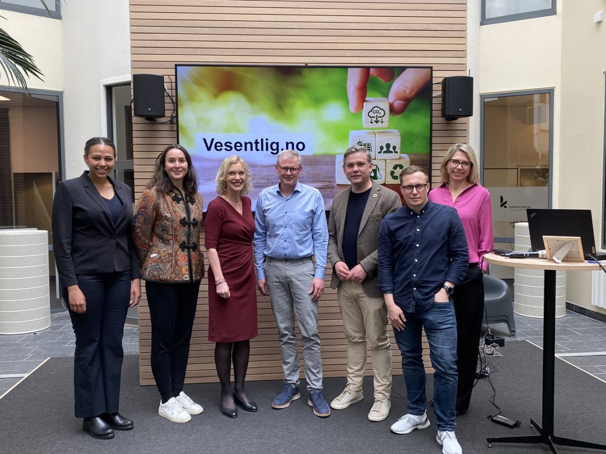 Innledere fra lanseringen står oppstilt foran en skjerm.