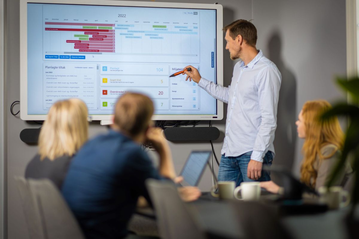 Foredragsholder som viser en graf på en skjerm i forbindelse med miljørapportering.