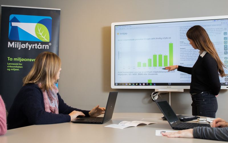 Dame som peker på graf på skjerm