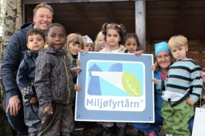 Barn i barnehagen står oppstilt og holder frem Miljøfyrtårn-diplom