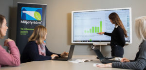 Dame som peker på graf på skjerm