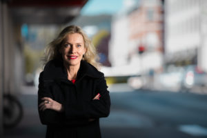 Dame med armene i kors poserer med bybakgrunn