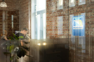 Bilde av Miljøfyrtårndiplom hengende i kontorlandskap og det skimtes en mann foran PC