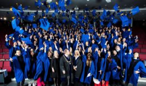 Stor gruppe studenter som feirer ved å kaste eksamenshatten av å kaste