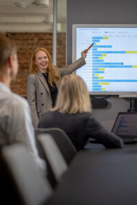 Bilde av smilende dame som peker på grafer på skjerm
