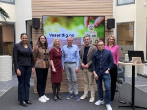 Innledere fra lanseringen står oppstilt foran en skjerm.