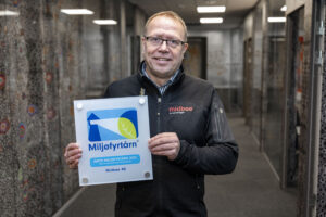 Runar Ullenes holder et Miljøfyrtårn-diplom med begge hender.