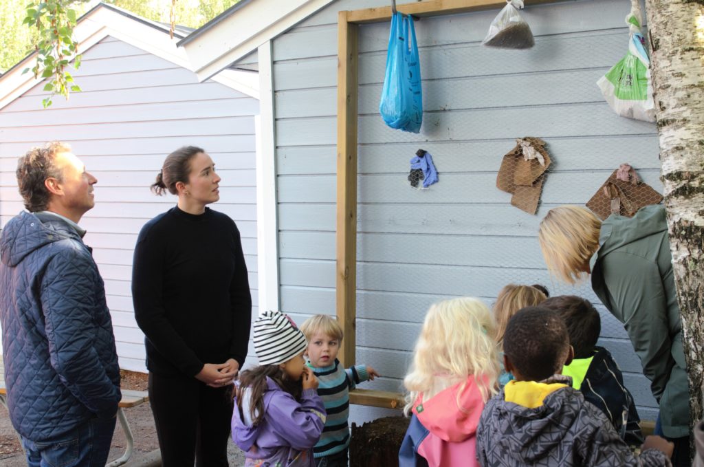 Barn og voksne ser på søppelveggen i barnehagen