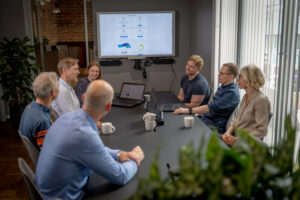 Bilde av en gruppe mennesker rundt et møtebord som diskuterer